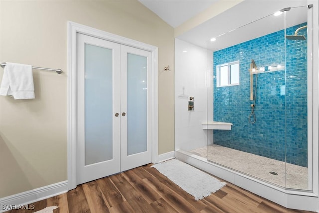 bathroom with hardwood / wood-style floors, tiled shower, and french doors