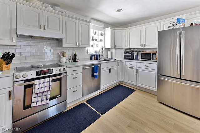 kitchen with white cabinetry, sink, stainless steel appliances, tasteful backsplash, and light wood-type flooring