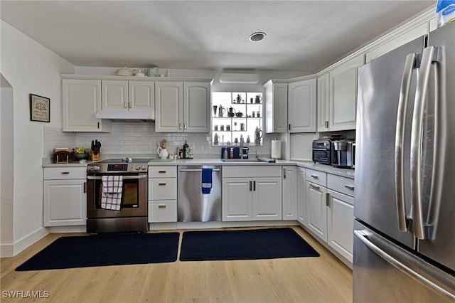 kitchen featuring white cabinets, sink, light hardwood / wood-style flooring, appliances with stainless steel finishes, and tasteful backsplash