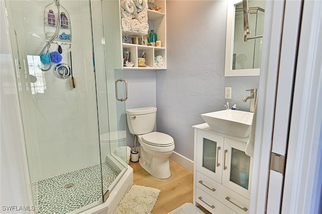 bathroom featuring vanity, hardwood / wood-style flooring, toilet, and a shower with door