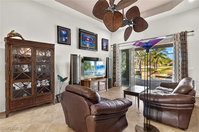 tiled living room featuring a tray ceiling and ceiling fan