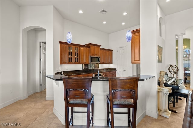 kitchen featuring decorative light fixtures, kitchen peninsula, a breakfast bar, and light tile patterned floors