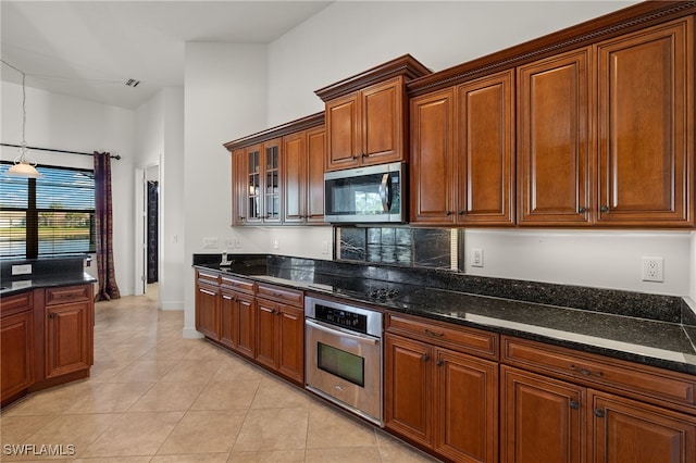 kitchen featuring pendant lighting, stainless steel appliances, light tile patterned floors, and dark stone countertops