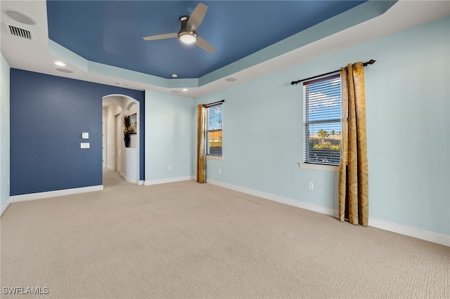 unfurnished room with a tray ceiling, ceiling fan, and light colored carpet