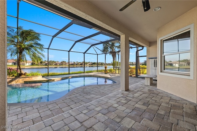 view of pool with glass enclosure, a patio area, a water view, and ceiling fan