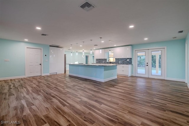 kitchen featuring white cabinetry, a kitchen island, hanging light fixtures, and light hardwood / wood-style floors