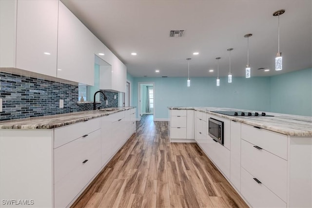 kitchen with light wood-type flooring, decorative light fixtures, white cabinetry, and sink