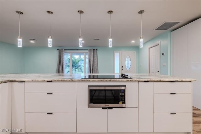 kitchen featuring black electric cooktop, light stone countertops, white cabinets, and hanging light fixtures