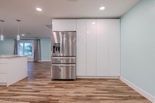 kitchen featuring stainless steel fridge, decorative light fixtures, white cabinetry, and light hardwood / wood-style floors