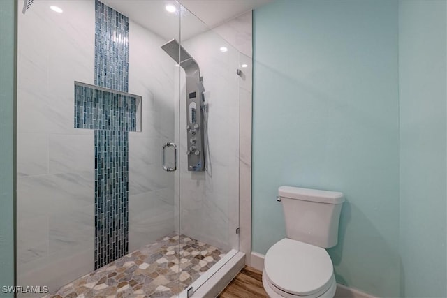 bathroom featuring wood-type flooring, a shower with shower door, and toilet