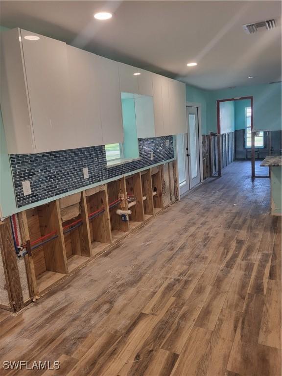 kitchen featuring white cabinets, decorative backsplash, and hardwood / wood-style flooring