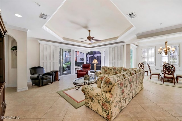 living room with ceiling fan with notable chandelier, light tile patterned floors, crown molding, and a tray ceiling