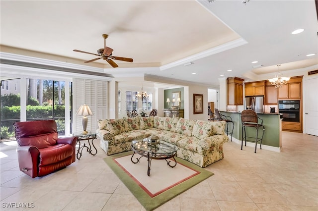 tiled living room featuring a raised ceiling, ceiling fan with notable chandelier, and ornamental molding