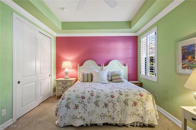 bedroom with ceiling fan, light colored carpet, and a closet