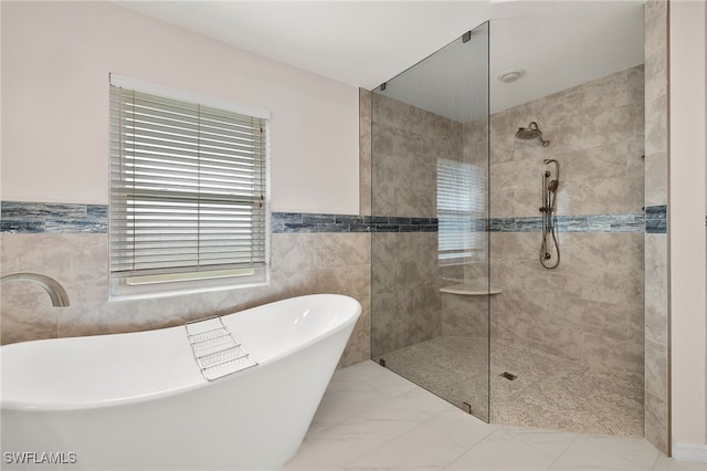 bathroom featuring plus walk in shower and tile walls