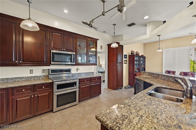 kitchen with sink, hanging light fixtures, ceiling fan, light stone countertops, and appliances with stainless steel finishes