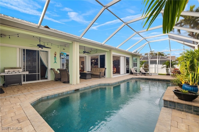 view of pool featuring glass enclosure, grilling area, an outdoor hangout area, ceiling fan, and a patio area