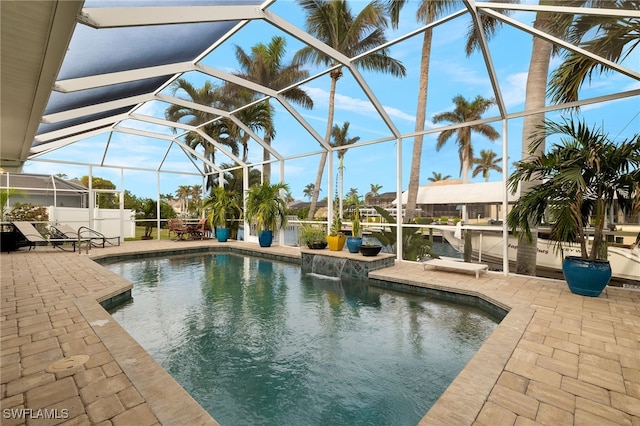 view of swimming pool featuring glass enclosure, a water view, and a patio