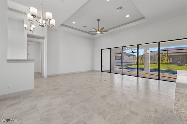 unfurnished room featuring a tray ceiling, a towering ceiling, and ceiling fan with notable chandelier