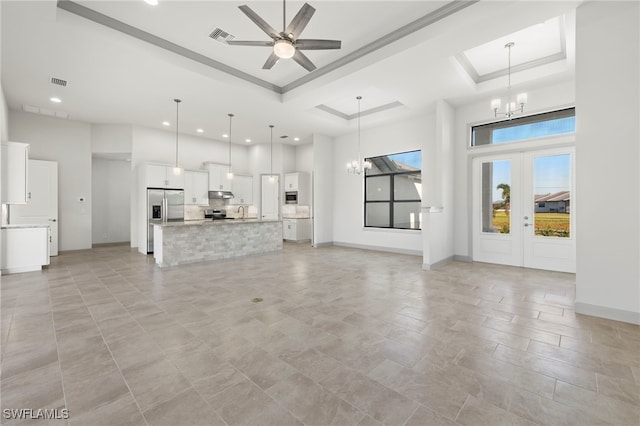 unfurnished living room with french doors, ceiling fan with notable chandelier, a raised ceiling, and crown molding