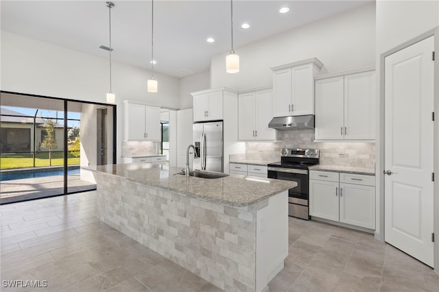 kitchen featuring white cabinets, a center island with sink, light stone countertops, and stainless steel appliances