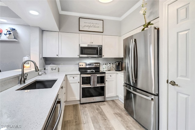 kitchen with sink, ornamental molding, appliances with stainless steel finishes, light hardwood / wood-style floors, and white cabinetry