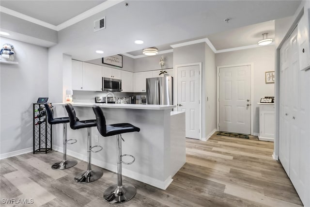 kitchen featuring a kitchen breakfast bar, light hardwood / wood-style flooring, white cabinetry, kitchen peninsula, and stainless steel appliances