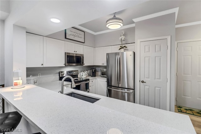 kitchen featuring white cabinets, sink, a breakfast bar area, kitchen peninsula, and stainless steel appliances