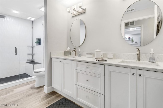 bathroom featuring wood-type flooring, vanity, toilet, and a shower with shower door