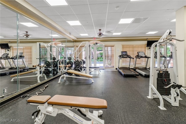 gym featuring a paneled ceiling, ceiling fan, and a healthy amount of sunlight