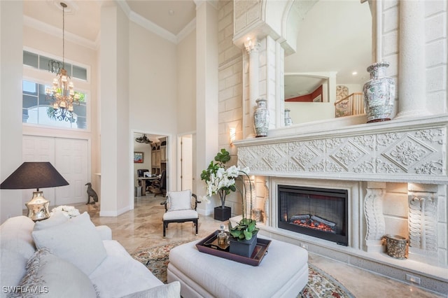 living room featuring a towering ceiling, decorative columns, ornamental molding, and a notable chandelier