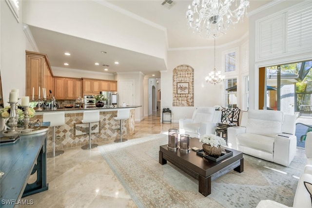 living room with a towering ceiling, ornamental molding, and an inviting chandelier