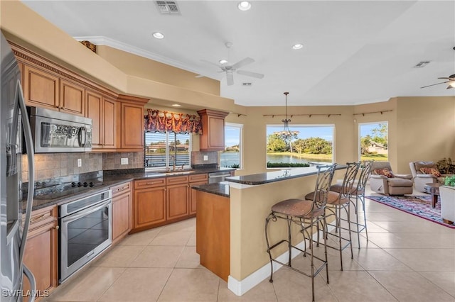 kitchen with decorative backsplash, appliances with stainless steel finishes, light tile patterned floors, and a wealth of natural light