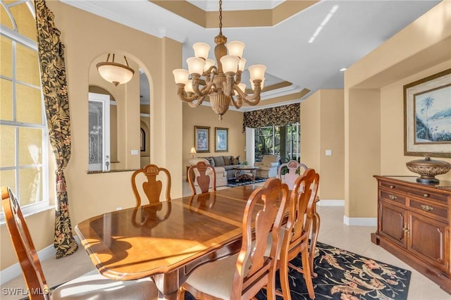 tiled dining area featuring a raised ceiling, a notable chandelier, and crown molding