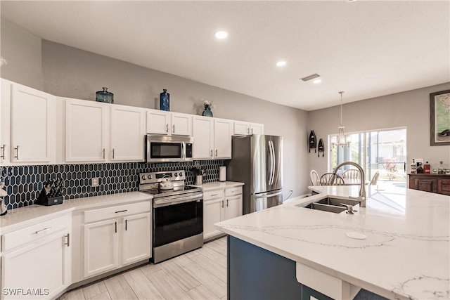 kitchen with white cabinets, hanging light fixtures, sink, and appliances with stainless steel finishes