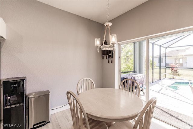 dining room with light wood-type flooring, an inviting chandelier, and lofted ceiling