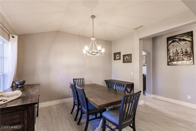 dining room with light hardwood / wood-style floors, an inviting chandelier, and lofted ceiling