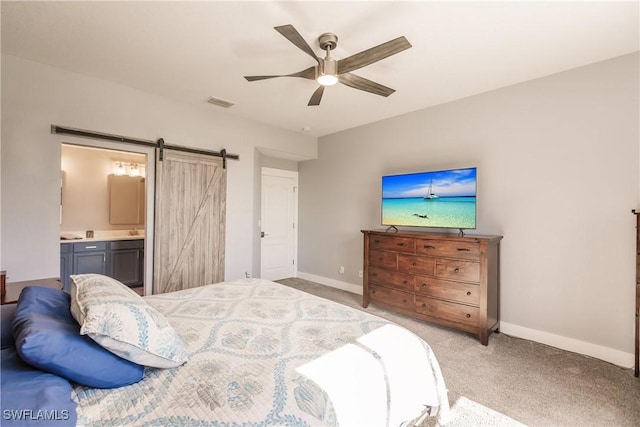 carpeted bedroom featuring ceiling fan, a barn door, and ensuite bath