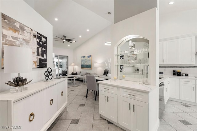 kitchen with white cabinets, ceiling fan, light stone countertops, tasteful backsplash, and light tile patterned flooring