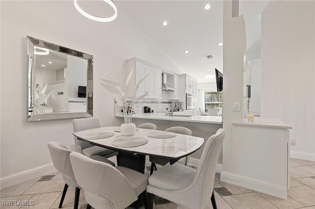 dining space featuring sink, light tile patterned flooring, and vaulted ceiling