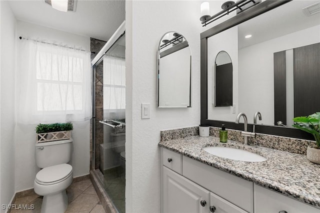 bathroom featuring tile patterned flooring, vanity, toilet, and walk in shower