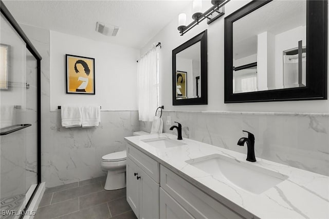 bathroom featuring vanity, tile patterned floors, toilet, a textured ceiling, and tile walls