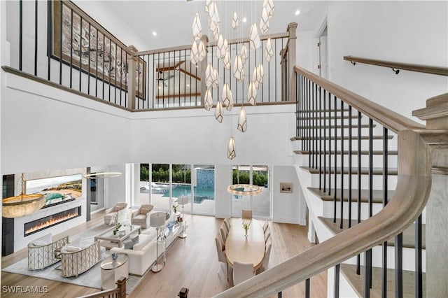 living room featuring a towering ceiling, a notable chandelier, and light wood-type flooring