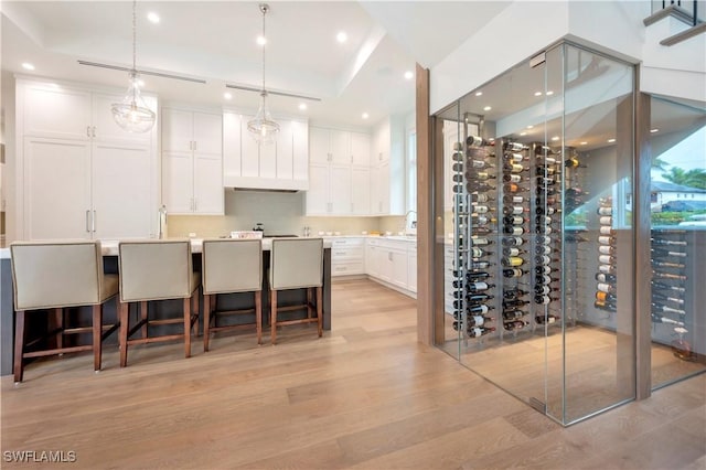 wine area with light wood-type flooring, a sink, and recessed lighting