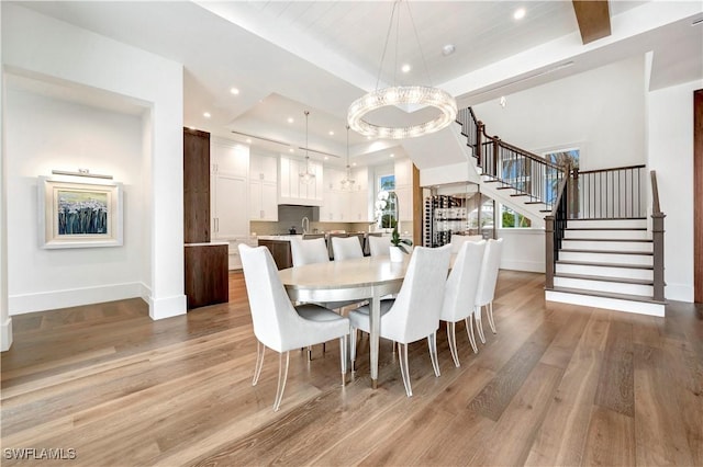 dining space featuring recessed lighting, a raised ceiling, light wood-style flooring, and stairs