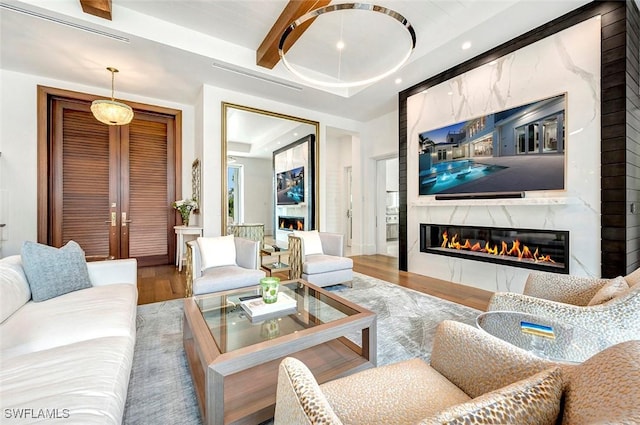 living room featuring recessed lighting, visible vents, a high end fireplace, wood finished floors, and beamed ceiling