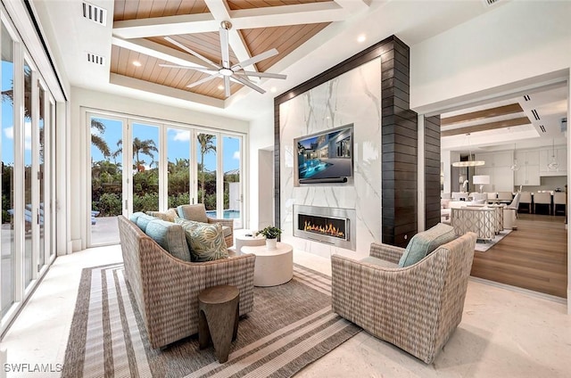 living area featuring visible vents, coffered ceiling, a premium fireplace, and a ceiling fan