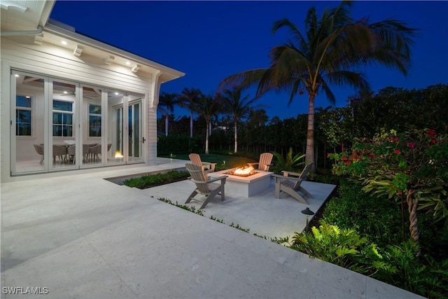 patio at night featuring an outdoor fire pit