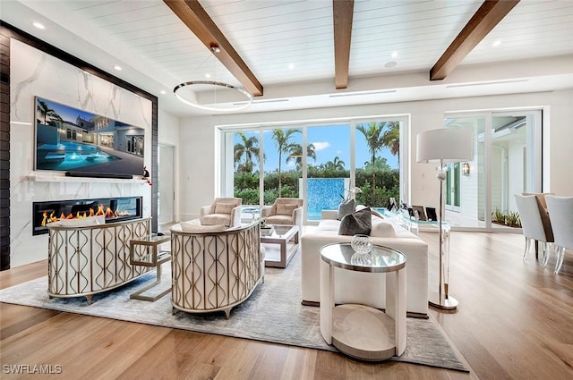 living area with light wood-style floors, a premium fireplace, beamed ceiling, and recessed lighting