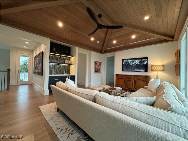 living area featuring baseboards, wood ceiling, wood finished floors, vaulted ceiling with beams, and a bar